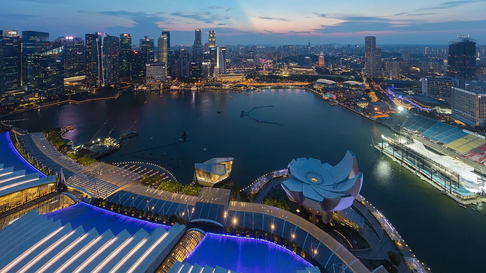 Vue aérienne du quartier d'affaires de Singapour au crépuscule, avec ses tours illuminées autour de la baie